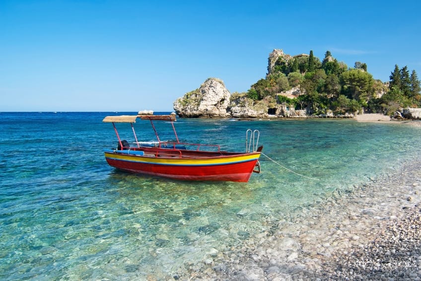 Colorful boat anchored in turquoise Caribbean beach water of Bahia de las Aguilas