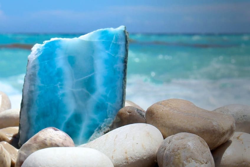 Unpolished Larimar slab against turquoise ocean waves