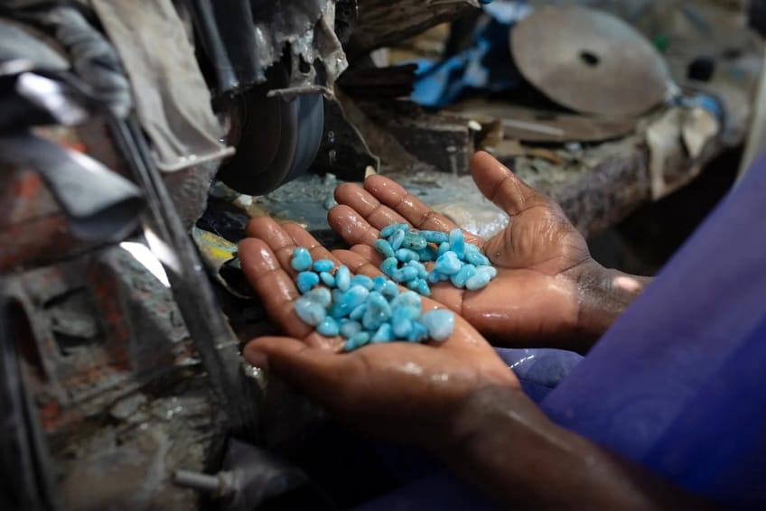 Hands holding finished Larimar stones at polishing station
