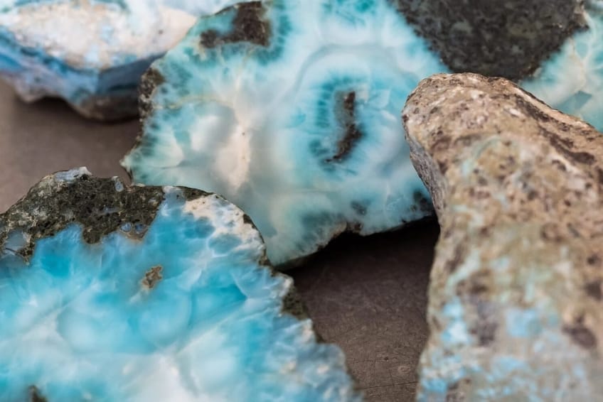 Close-up of blue geode rocks with white crystalline centers and rough outer crusts in brown and gray tones.