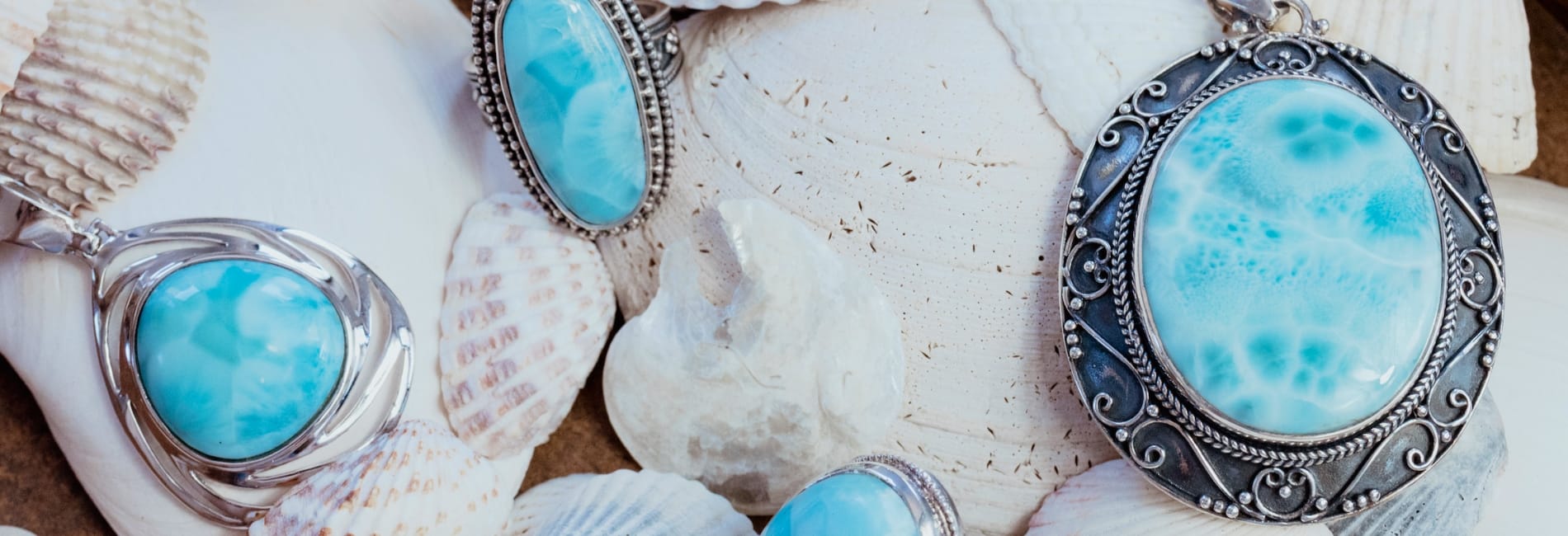Genuine Larimar pendants and rings displayed on shells