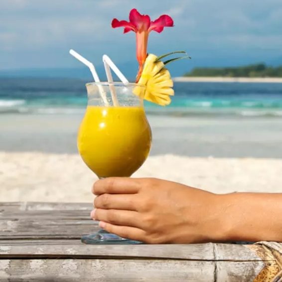 Holding a tropical mango cocktail on Baby Beach in Cabo Rojo