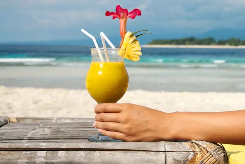 Holding a tropical mango cocktail on Baby Beach in Cabo Rojo